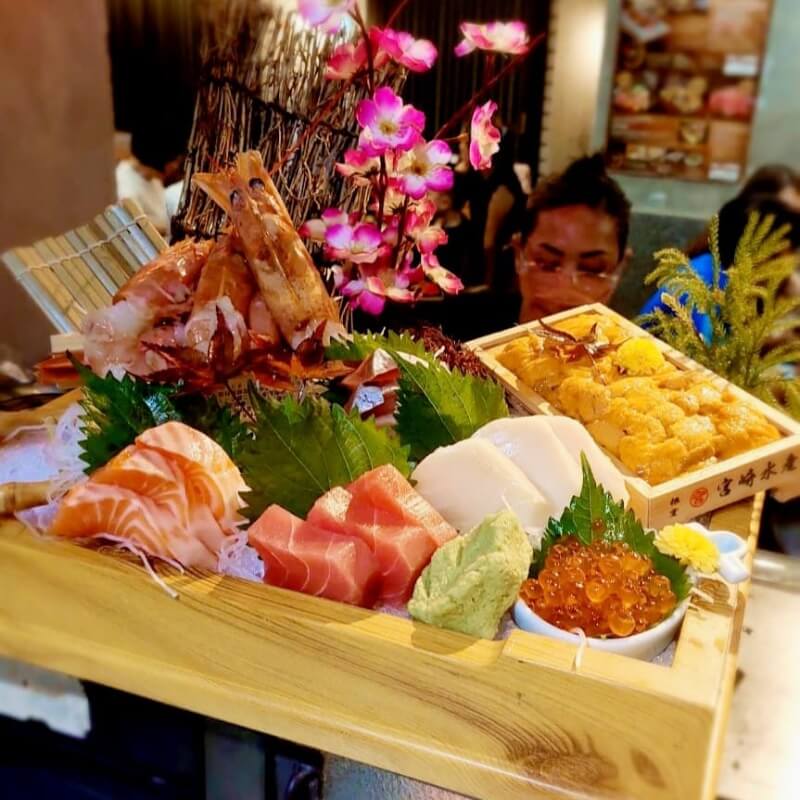 sashimi laid out in a wooden box with flowers