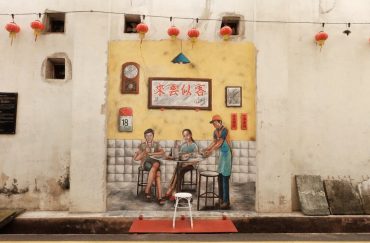 two people seated at coffee shop being served mural