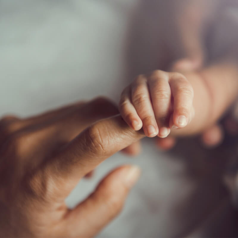 a mum holding babys hand