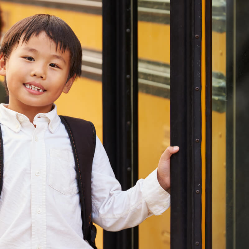 A boy standing in front of a school bus