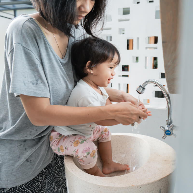 a mother teaching toddler hand washing