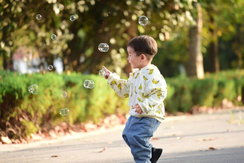 little boy chasing bubbles