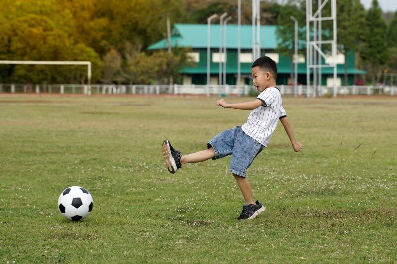 little boy kicking football