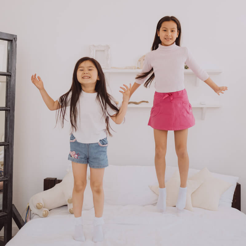 girls jumping on the bed