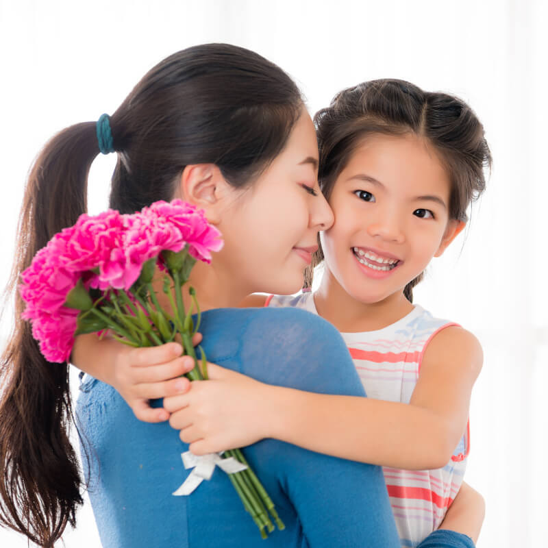 a mum hugging her daughter holding flower