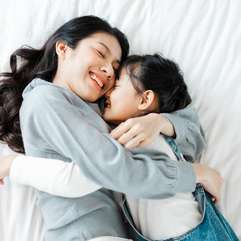 mother and daughter cuddling on bed