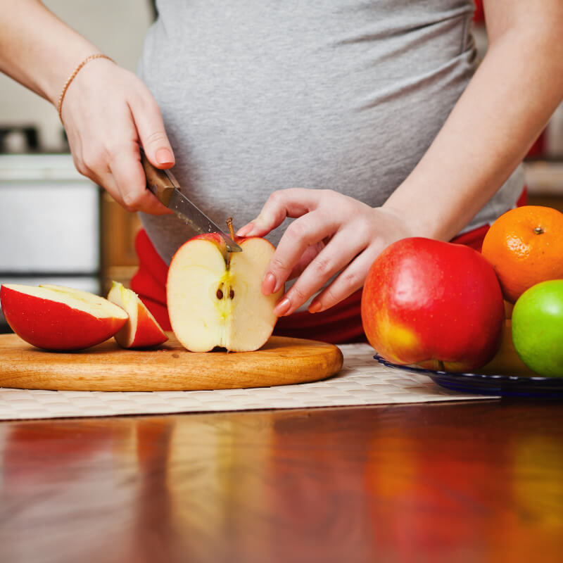 a pregnant lady cutting fruits