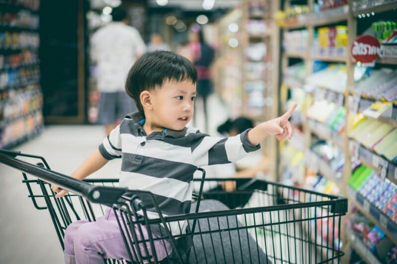 little boy in shopping cart pointing