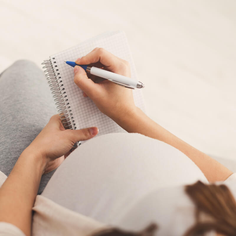 A pregnant lady writing a journal