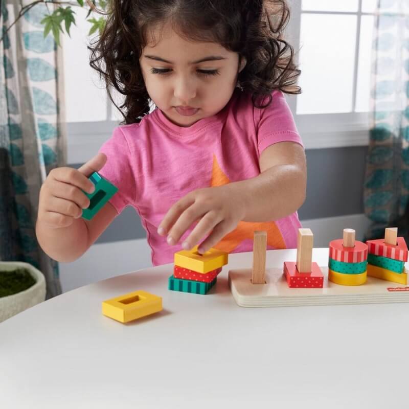 Female toddler playing wooden shape stacker 