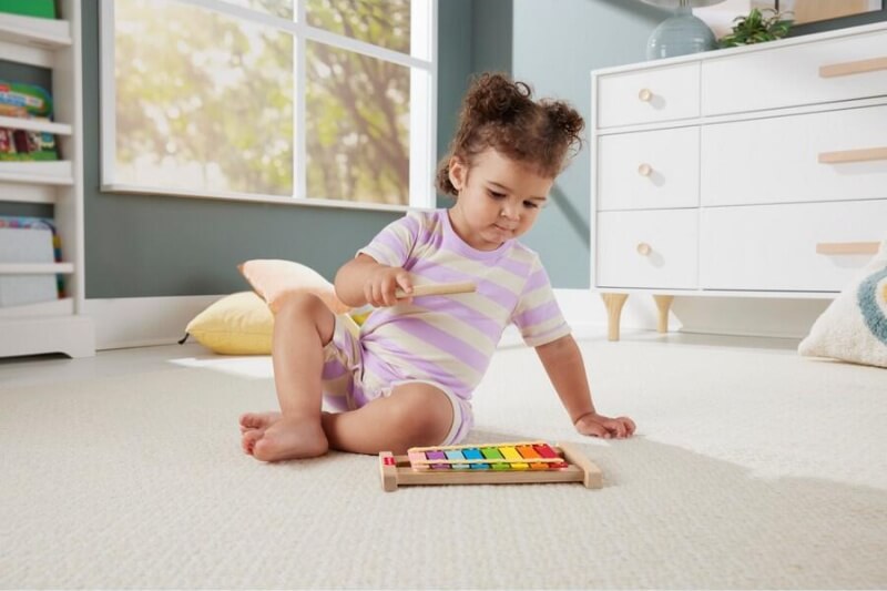 female toddler playing wooden xylophone musical instrument for babies