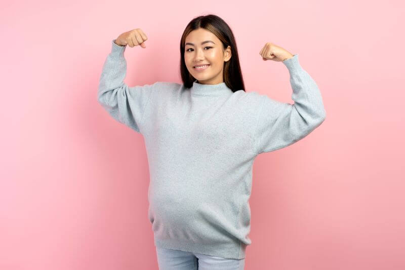 strong pregnant woman shows bicep