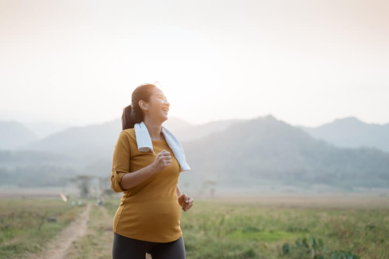 pregnant woman enjoys exercising outdoors with sunlight