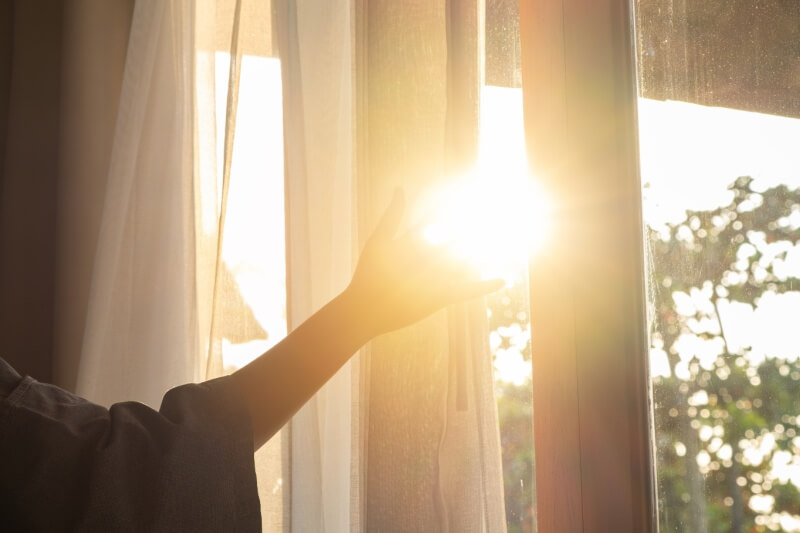 woman holding curtain enjoying sunlight