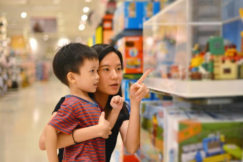 little boy looking at toys with mother