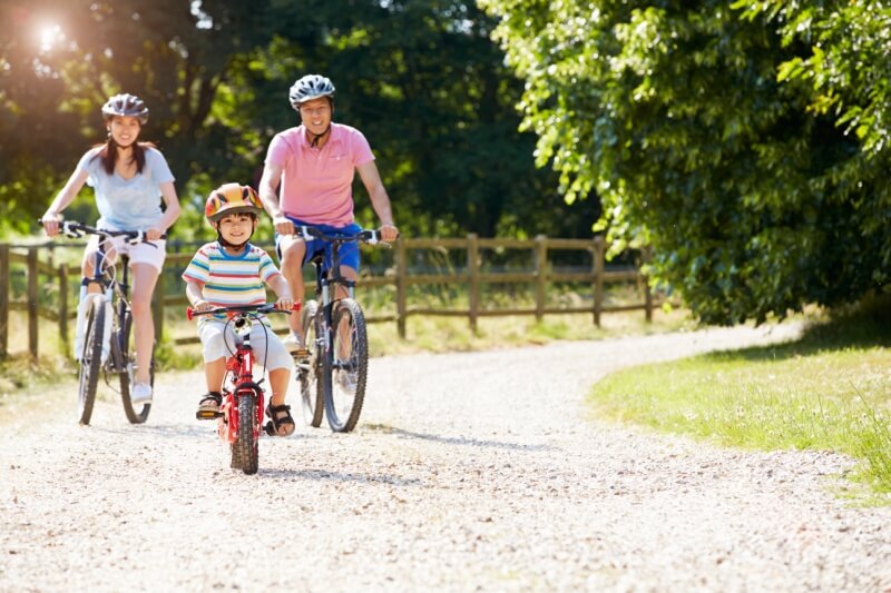 family riding bicycle keeping safe and using helmet