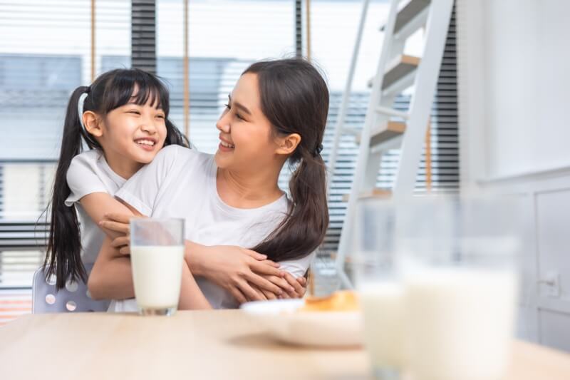 mother and daughter enjoying glass of milk for breakfast