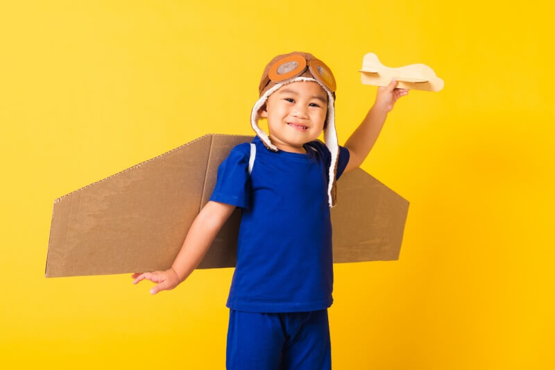 young boy with imagination making airplane from cardboard