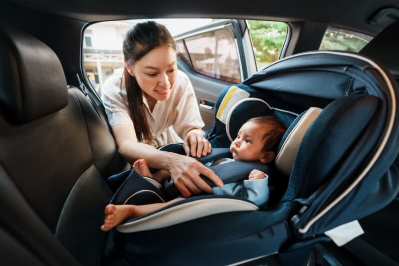 mother putting child in car seat