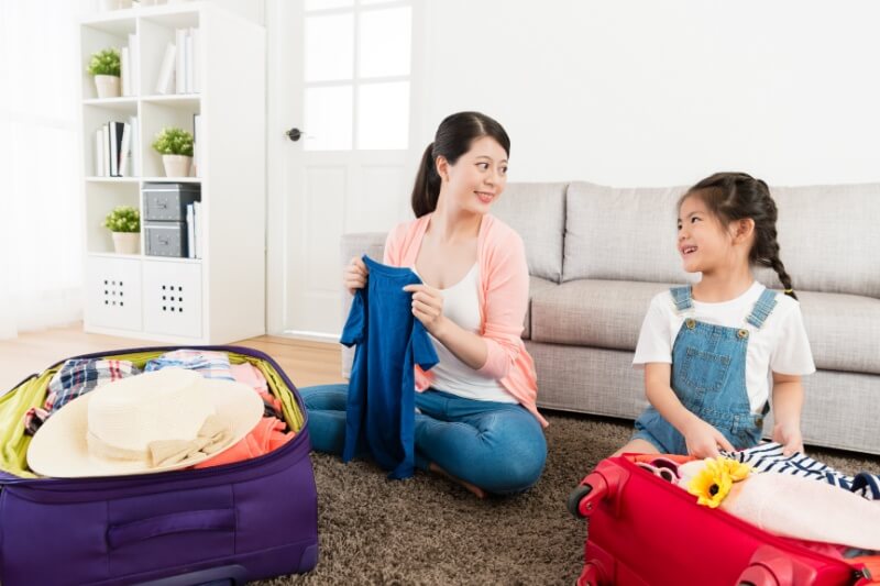 mother folding clothes with young daughter