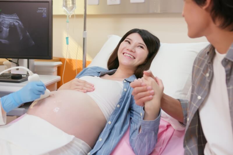 pregnant woman holding hand with husband in hospital