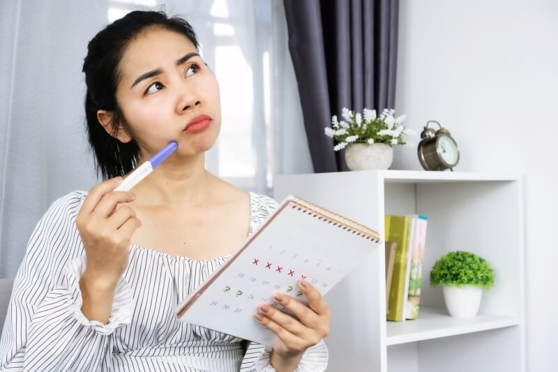 woman with pregnancy test holding calendar