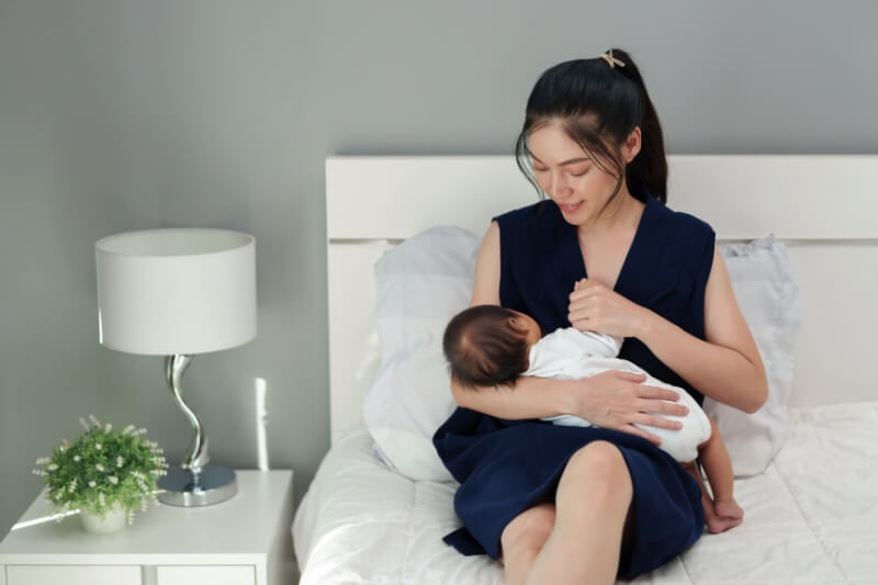 mother breastfeeding child on the bed