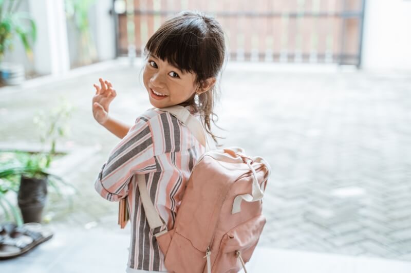 toddler saying goodbye while carrying a backpack