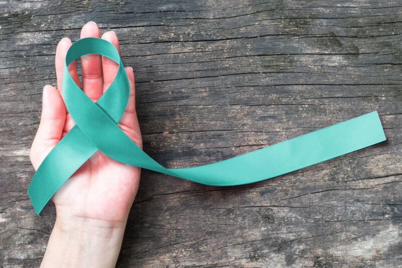 Teal ribbon awareness on woman's hand for Ovarian Cancer