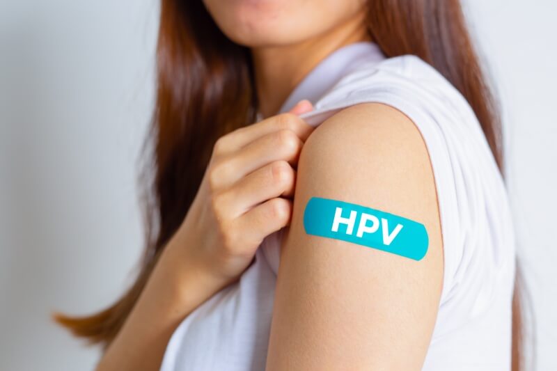  woman showing off an blue bandage after receiving the HPV vaccine