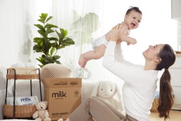 baby being held and carried by mother with diapers in the background