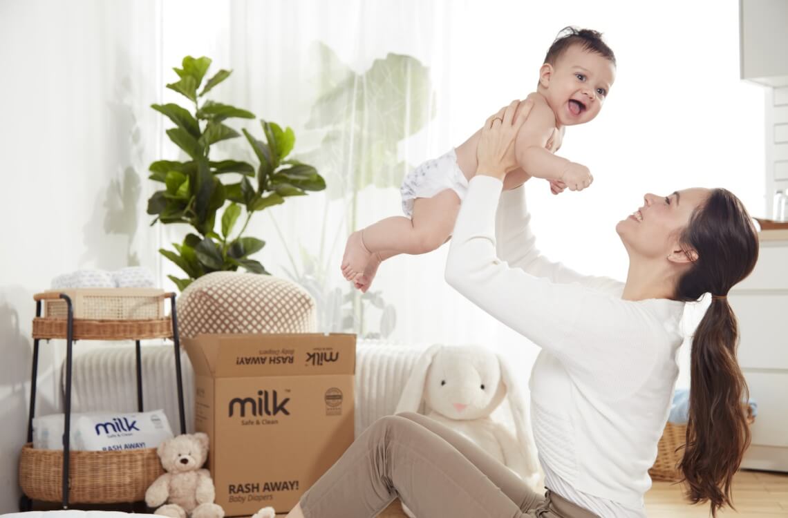 baby being held and carried by mother with diapers in the background