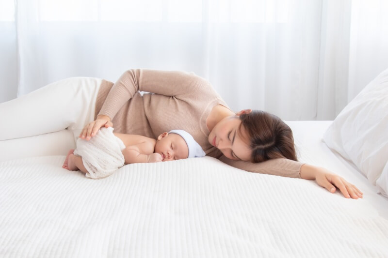 mother resting with baby on the bed