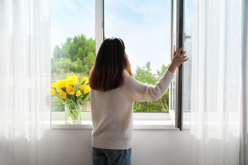 woman opening windows for fresh air