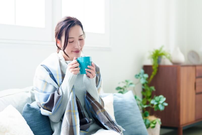 woman with blanket over shoulder and drinking some tea