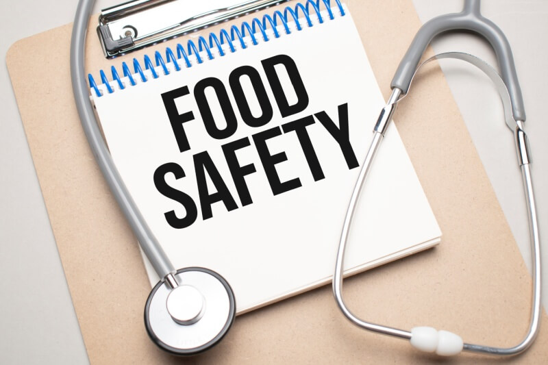 White notepad with the words food safety and a stethoscope on a blue background