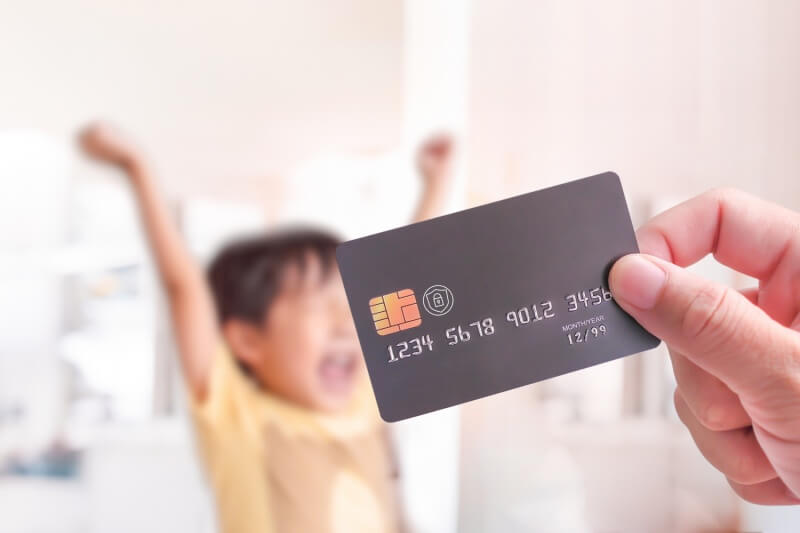 parent holding credit card in front of happy child