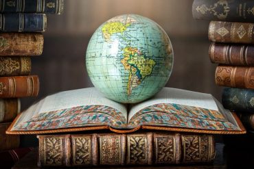 Old globe lying on an open book in a library