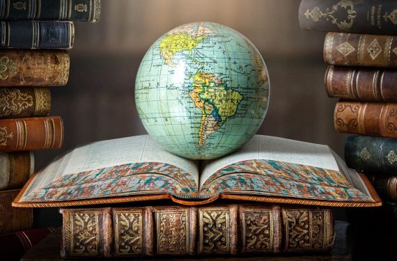 Old globe lying on an open book in a library