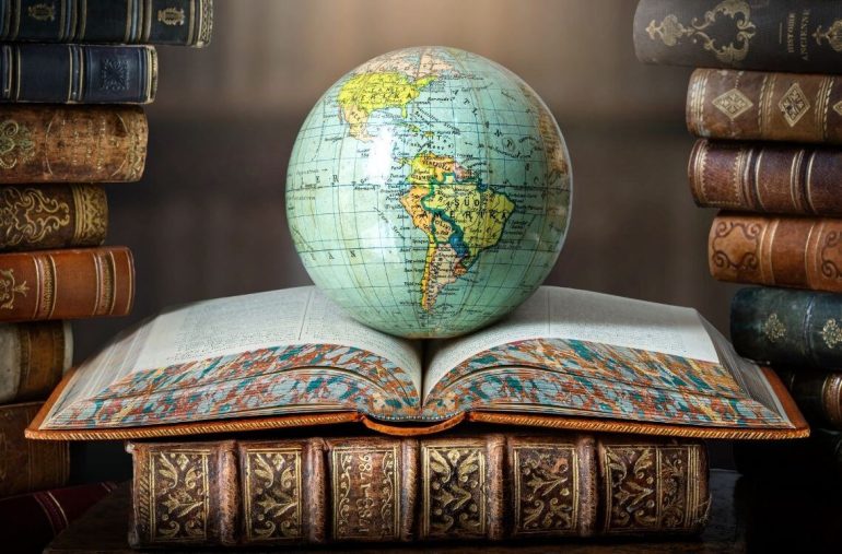 Old globe lying on an open book in a library