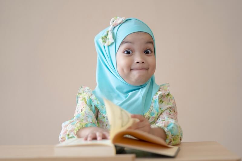 young girl in headscarf happy reading