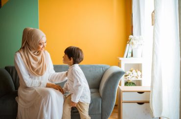 mom chats with little boy sitting on the sofa in the living room