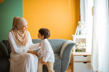 mom chats with little boy sitting on the sofa in the living room