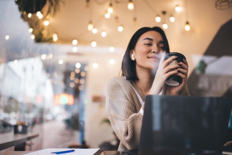 Young millennial brunette woman wearing earphones sitting at table