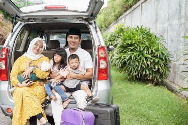 family sitting on car trunk together