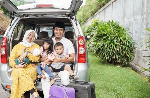 family sitting on car trunk together