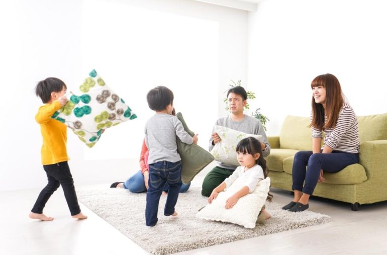 children playing pillow fight with parents in the room