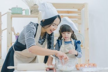 mother and daughter in chef hat baking in the kitchen