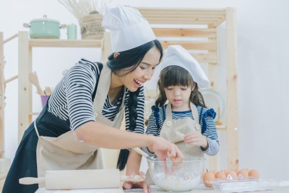 mother and daughter in chef hat baking in the kitchen