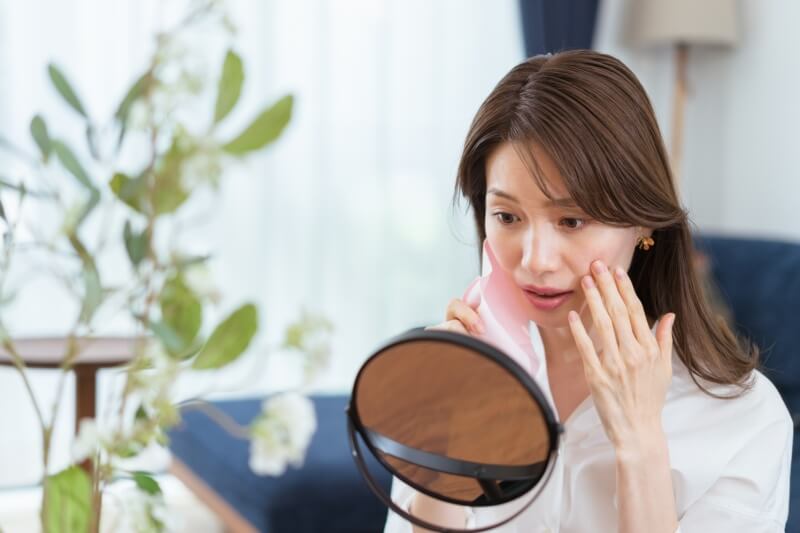 women checking mirror for signs of ageing
